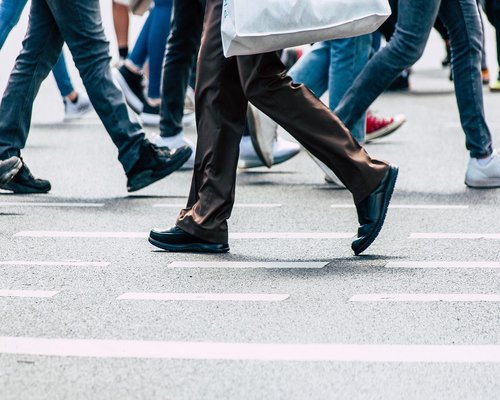 Detail of comfortable walking shoes stepping on a paved urban sidewalk